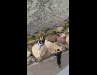 Woman black leather jacket flip hair photo shoot rocks seaside