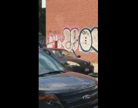 Man plays the trumpet in black Toyota car with door open on the street