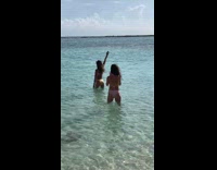 Woman in yellow bikini spreads hand at the beach