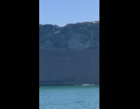 Guy backflip top of rock blue ocean 