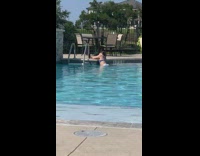 Woman in bikini poses on the poolside with a camera