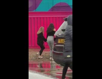 Two girls grey pants dance purple wall