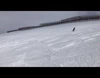 Snowboarder front flips over ledge, lands but then falls