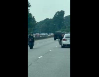 Man in car films woman on motorcycle