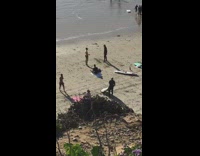 two men on beach one learns surfing on sand