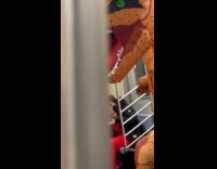 Collab Subway Creatures - Person wear inflatable dinosaur costume ride train with another pink inflatable costume