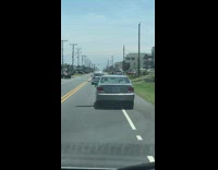 Silver car driving with blue surfboard out of driver rear passenger window