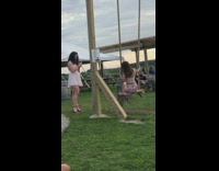 Pink skirt girl sits wood swing grass 