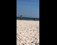 Woman silver bikini hands over head beach