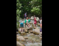 Woman in white and green top sits on the rock