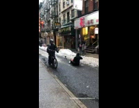 Guy sits on street and plays drum 