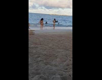Two women in white and black bikini poses at the beach