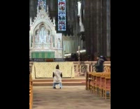 Woman kneels in church for a video