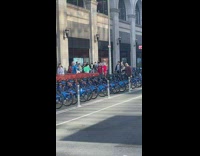 Two people holding clothing rack run in circle 