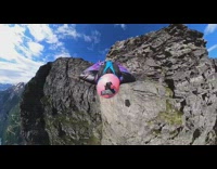 Pink helmet girl wingsuit jumps cliff parachute