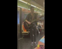 Guy plays acoustic guitar and sings on subway 