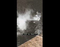 White bubbles with steam clouds coming out of water side of street drain