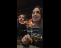 Women give water shots to men in bar