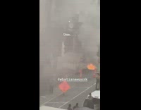 Fire inside manhole on street, firetrucks distinguish flames