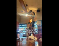 Womann dusting off ceiling fan leans head backwards strangely