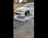 Man Cleans Car with Brush at Garage