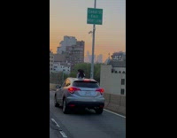 Girl films herself outside of sunroof during sunset