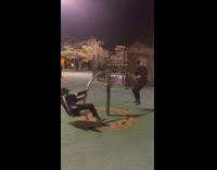 Two people playing on see saw swing in park at night 