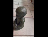 Dog barks and growls at baby statue on tile floor