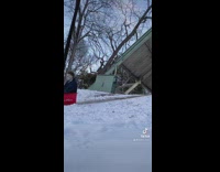 Guy wearing michael myers rides sled downhill 