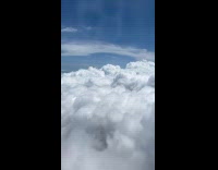 Airplane Flies Beside Fluffy Clouds in Sky