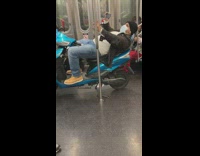 Guy riding subway leans back on scooter and watches video