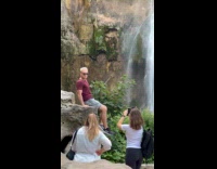 Collab IITW - Man maroon shirt sunglasses poses front of waterfalls