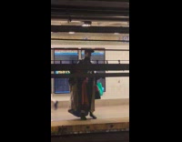 Guy wearing coat sings at subway platform