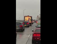Back of pickup truck displays hip hop music video on TV screen while driving on the freeway