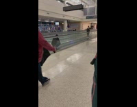 Man crouches at the walkalator at the airport