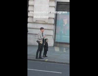 Lady pretends to read newspaper by curb