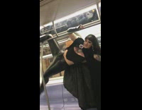 Tattooed woman all black cape leather hanging subway train