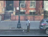 Bald guy sweeps neighborhood street with broom 