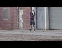 Guy lifts metal traffic barrier behind back 