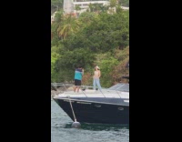 Woman in cowboy hat and bra poses at the boat