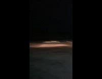 Silver car jumps over ramp at night 