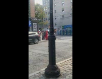 Man pushes dolly cart with speakers playing music through street