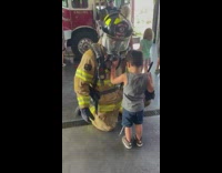 Blind boy touches the equipment and gears of the fireman