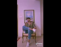 Guy sits down changes outfits brown chair 