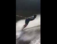 Woman waterskis on side of boat turns around
