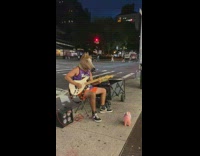 Guy plays guitar on sidewalk wearing horse head 
