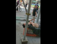 Man sleeps with shirt unbuttoned on sidewalk 