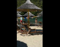 Woman in black bikini squats at beach