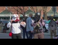Two people wearing mandalorian masks clap singer