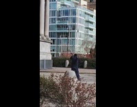 Guy at park blows into horn instrument 